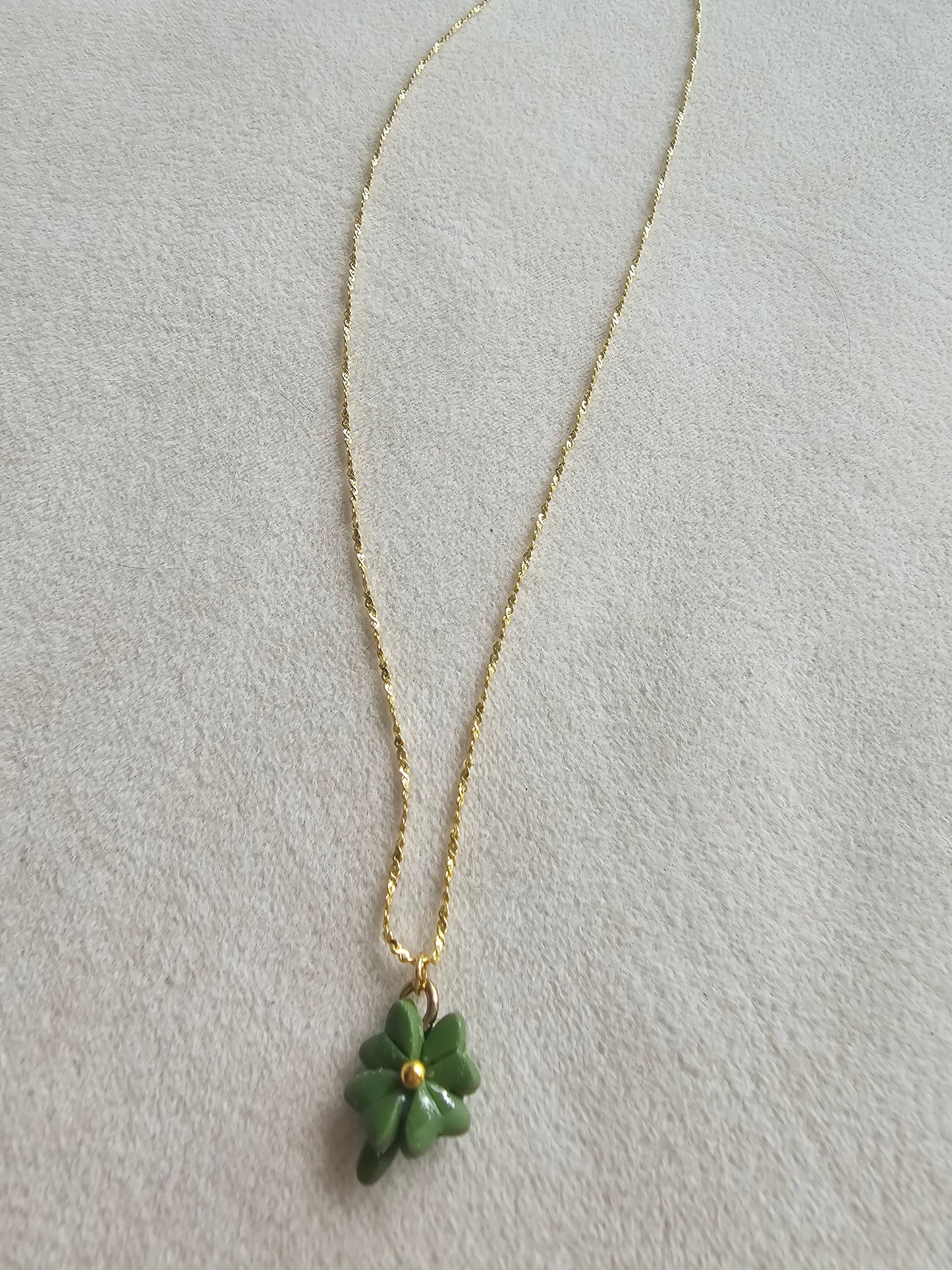 Gold necklace with a green pendant on a light gray background