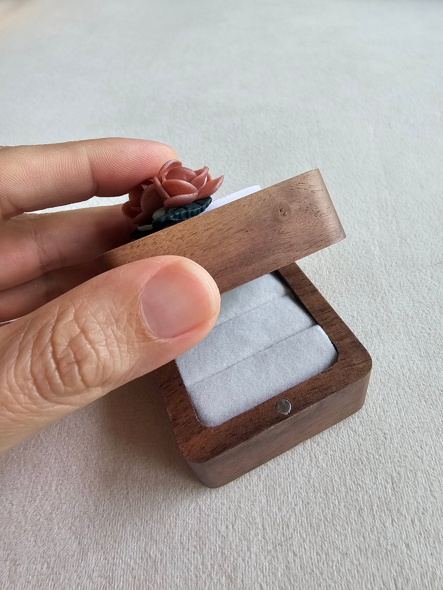Wooden jewelry box held by a hand on a light gray background