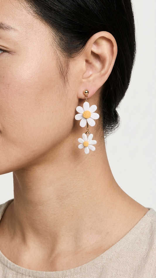 Close-up of a person wearing white flower-shaped earrings on a plain background