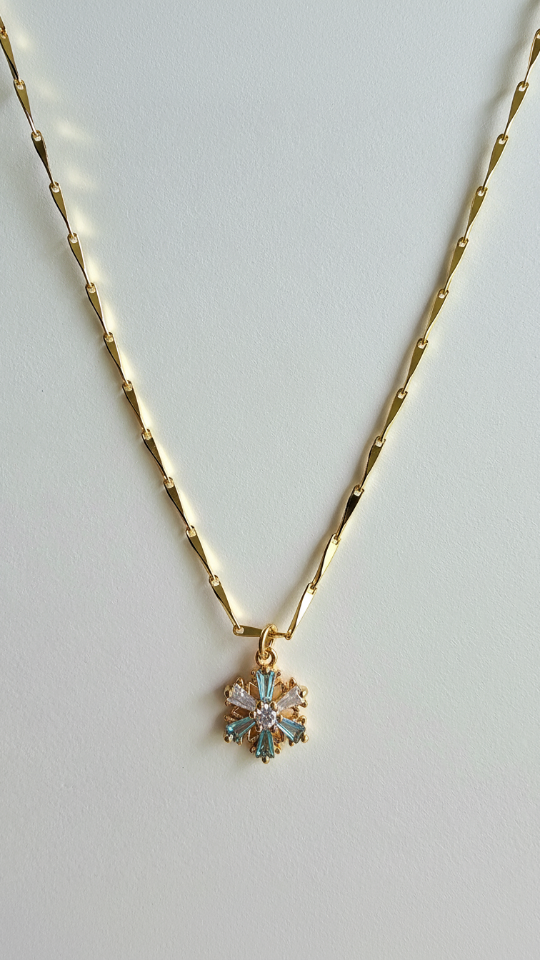 Gold necklace with a snowflake pendant on a light gray background