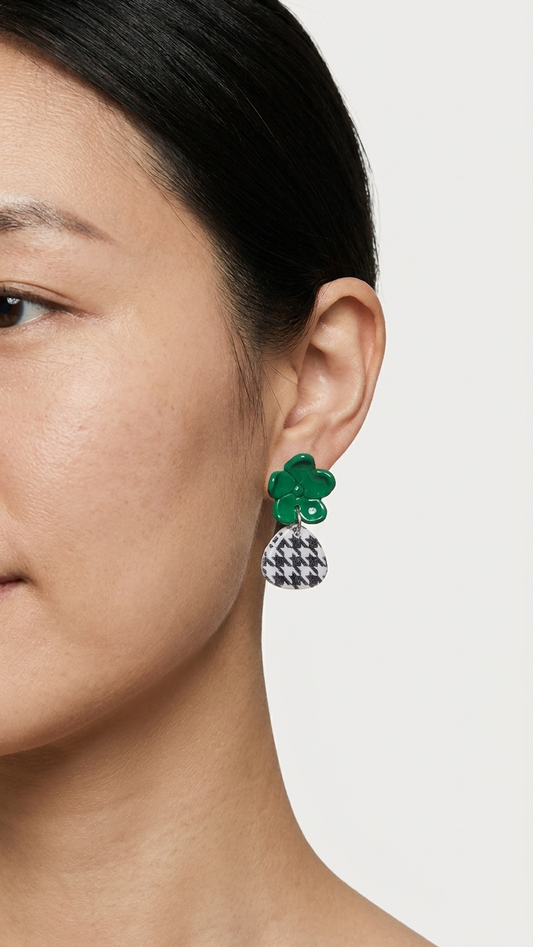 Close-up of a person wearing green floral earrings with a white background