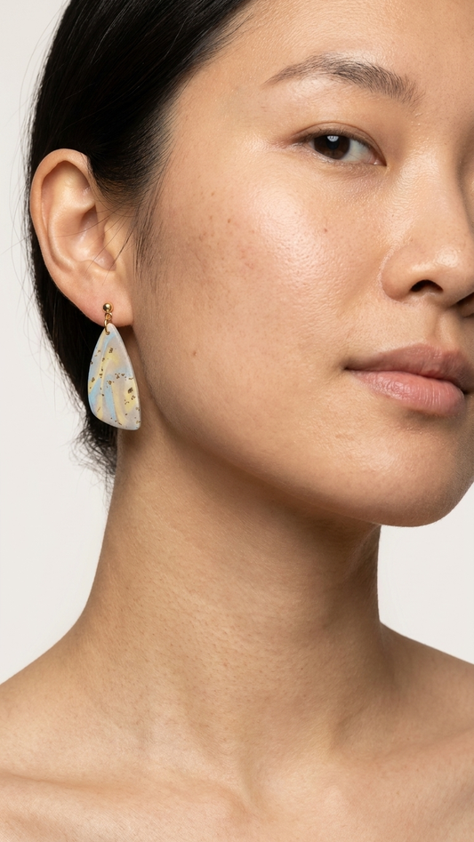 Close-up of a woman wearing a teardrop-shaped earring on a plain background