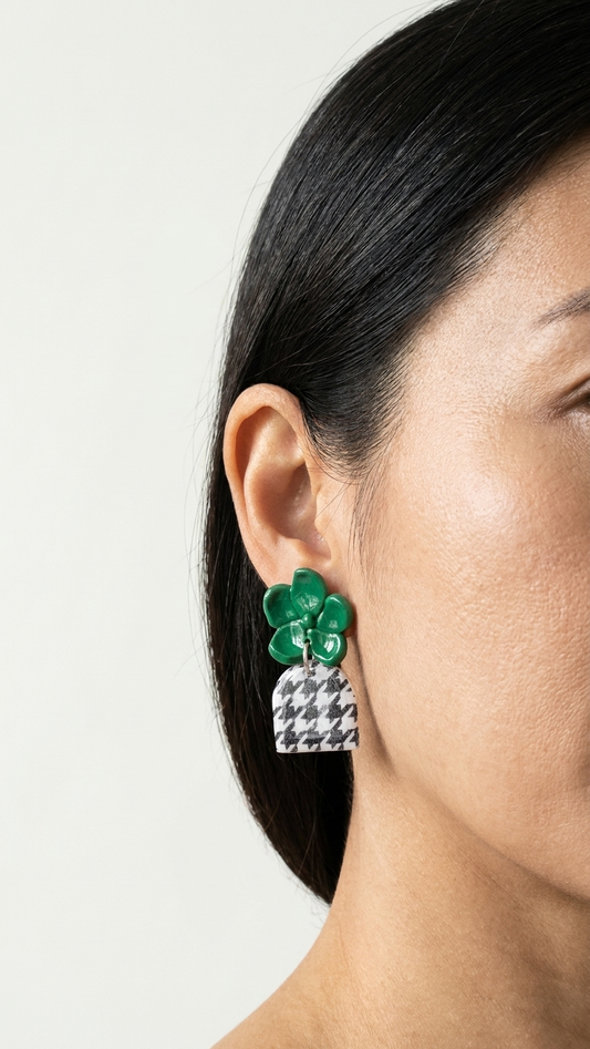 Close-up of a person wearing green floral earrings with a neutral background