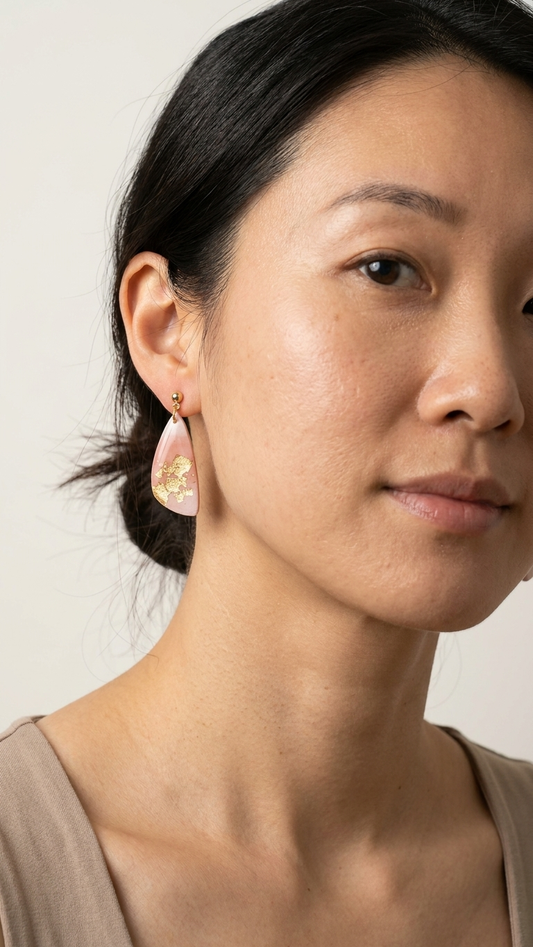 Close-up of a woman wearing gold earrings against a neutral background