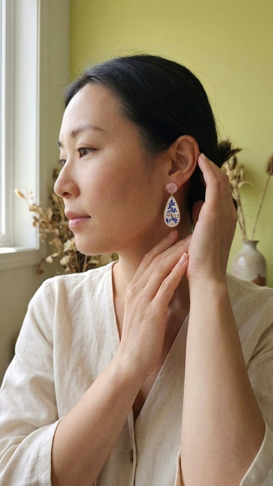 Woman wearing a decorative earring indoors with a green wall and window in the background