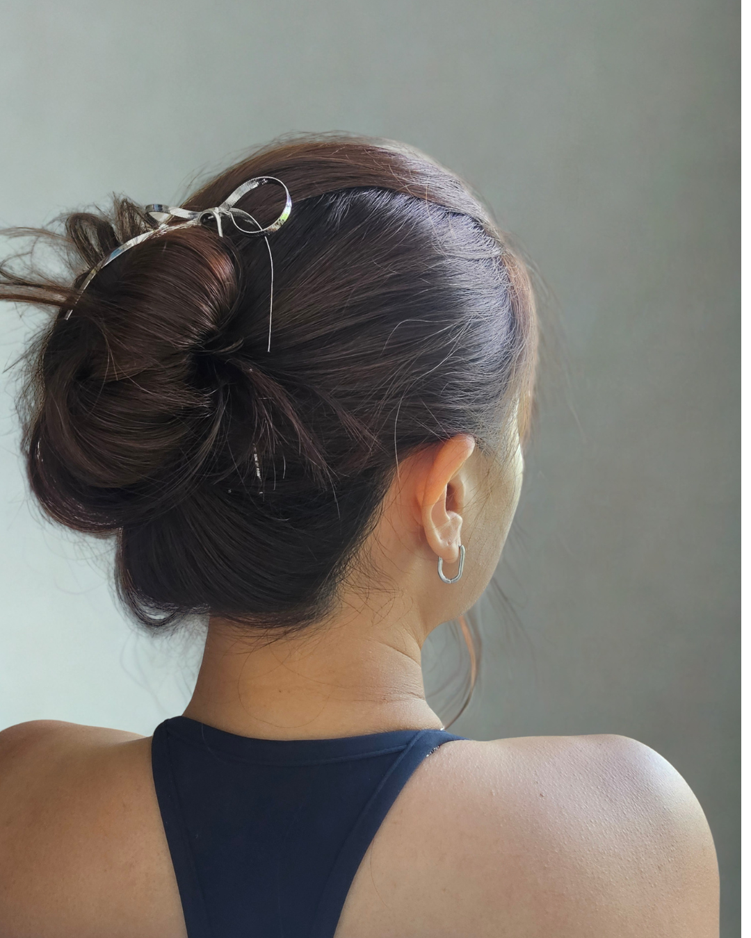 Back view of a person with styled hair against a neutral background