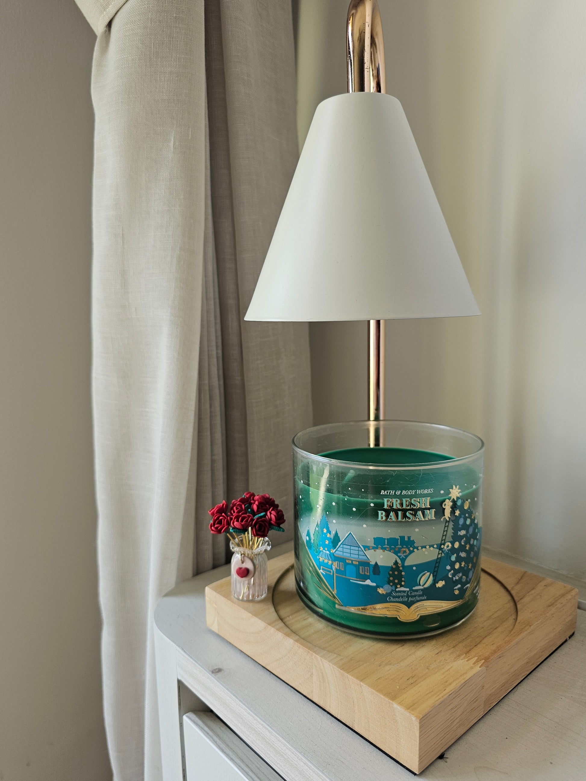 Candle with decorative label on a shelf next to a lamp