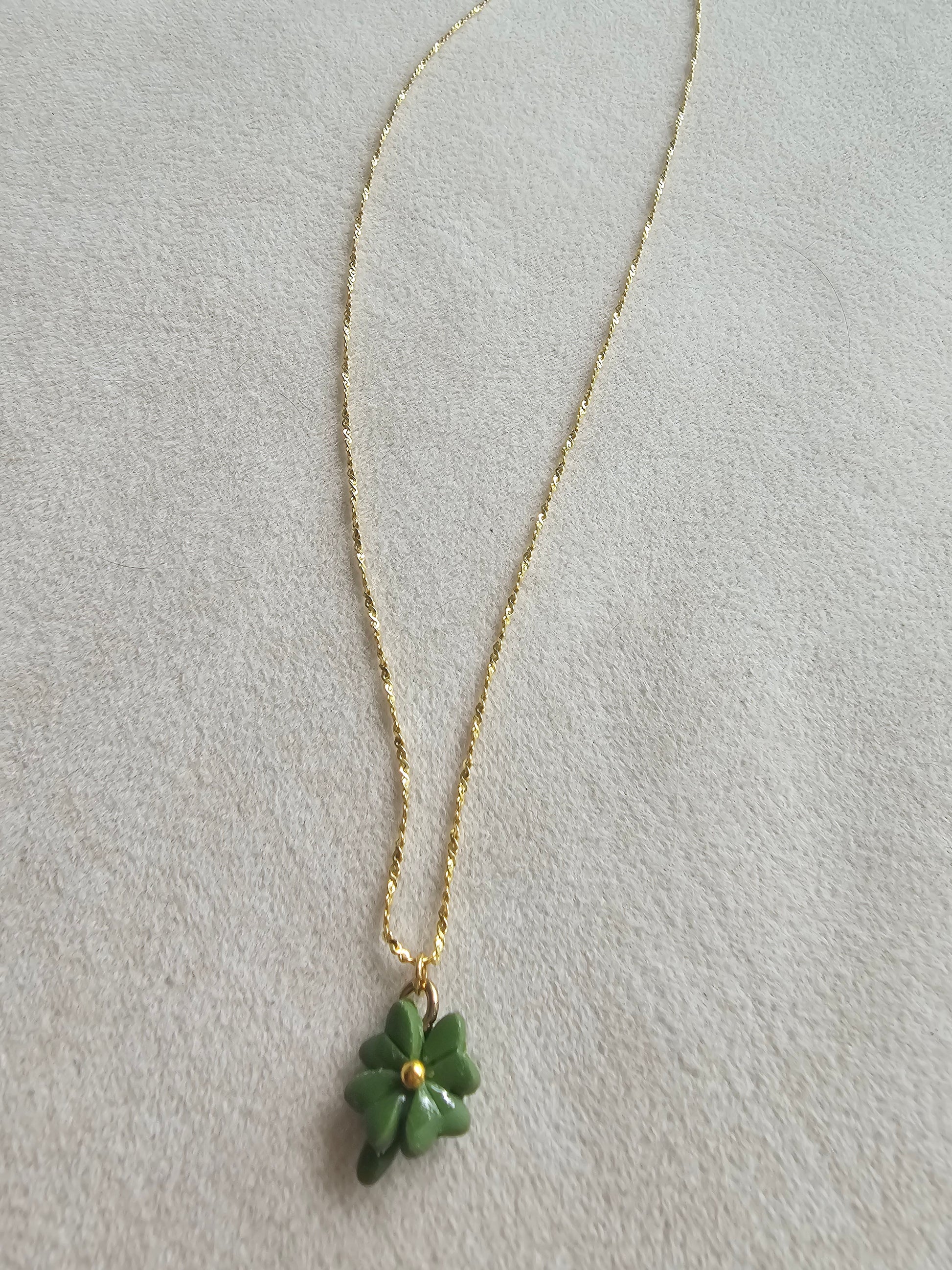 Gold necklace with a green pendant on a light gray background