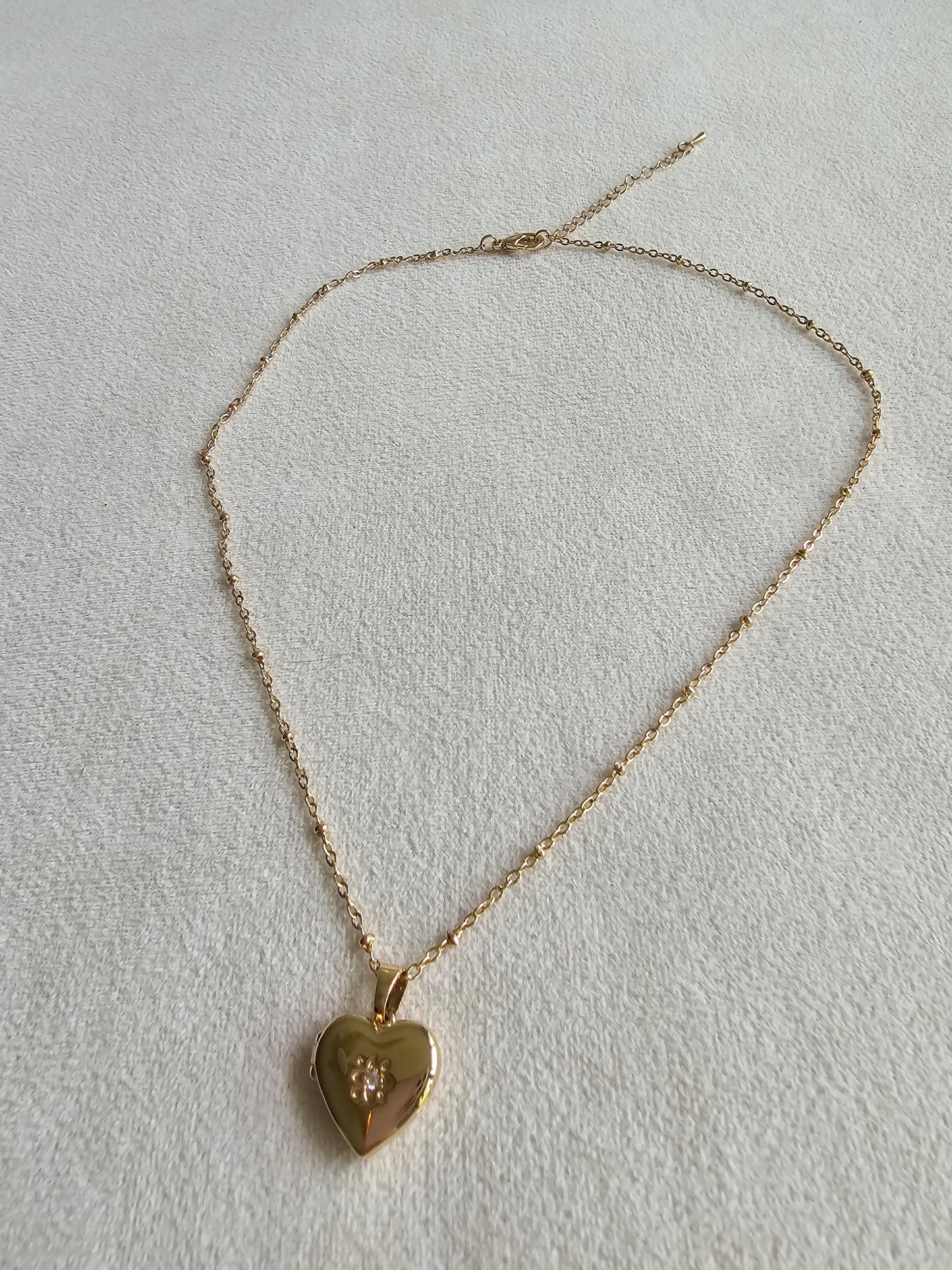 Gold heart-shaped pendant necklace on a light gray background