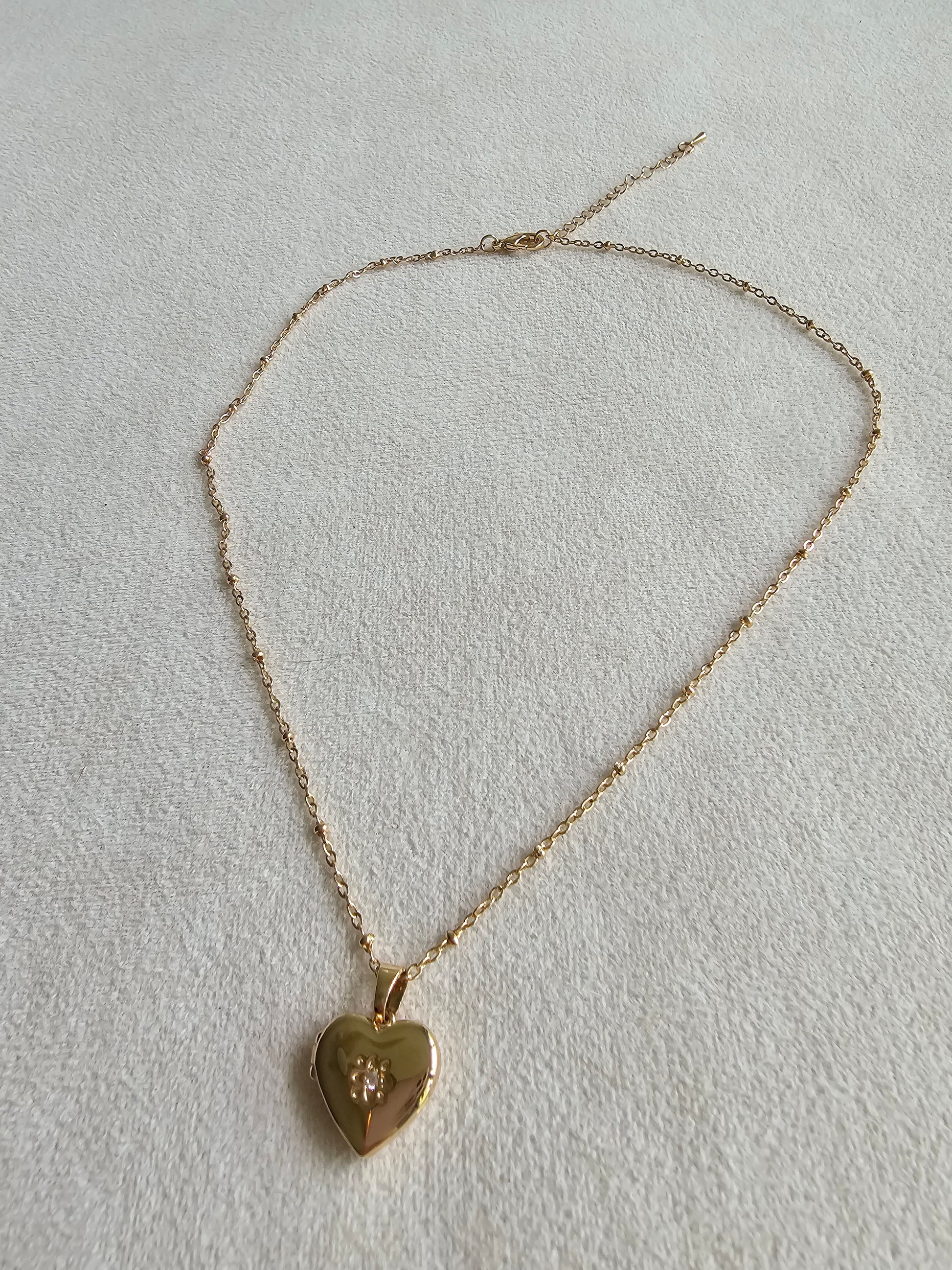 Gold heart-shaped pendant necklace on a light gray background