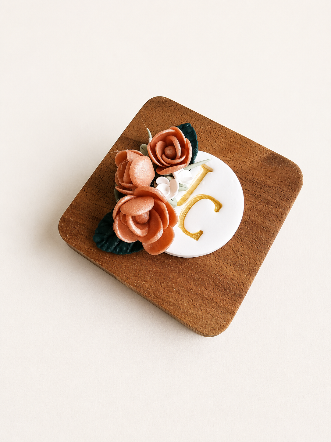 Wooden coaster with floral design and letter 'C' on a white background