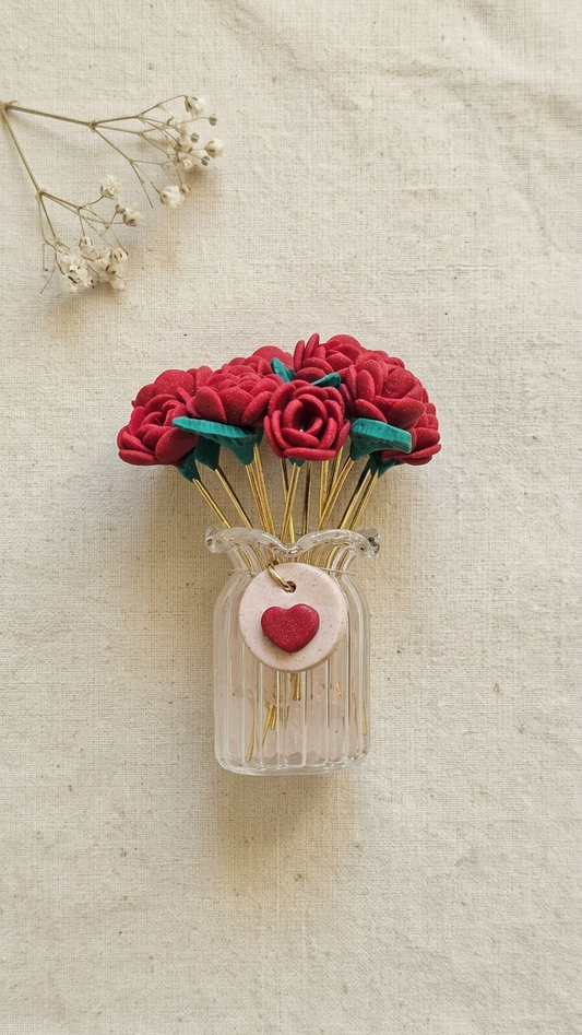 Decorative wall art with red flowers in a clear vase on a textured beige background
