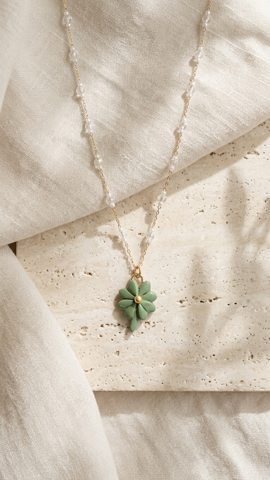 Necklace with a green pendant on a textured beige surface