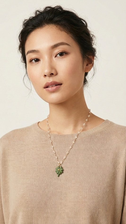Woman wearing a necklace with a green pendant against a neutral background
