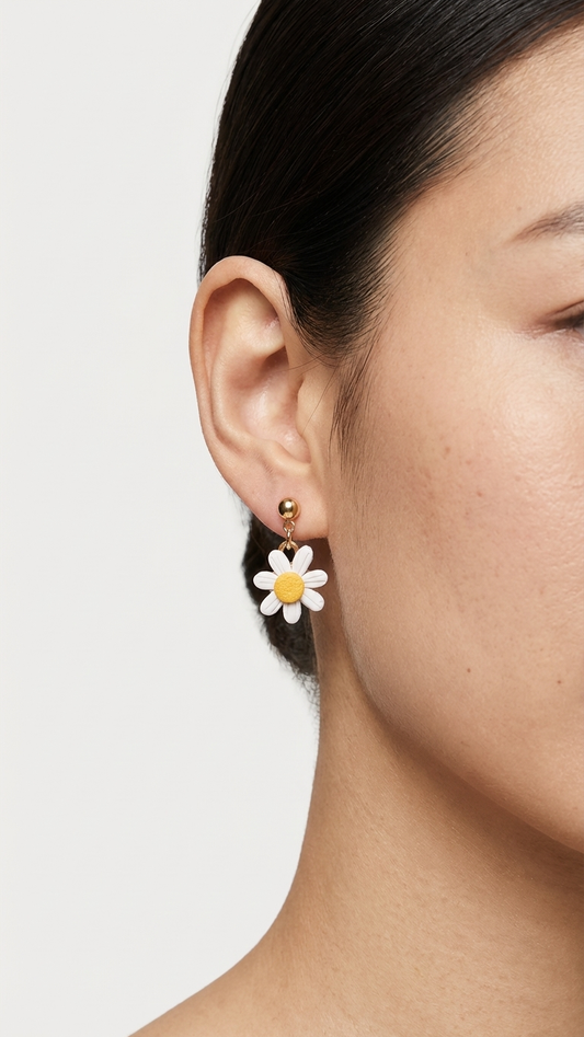 Close-up of a person wearing a daisy flower earring on a plain background