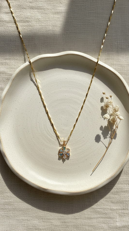 Necklace with a pendant on a ceramic dish with dried flowers