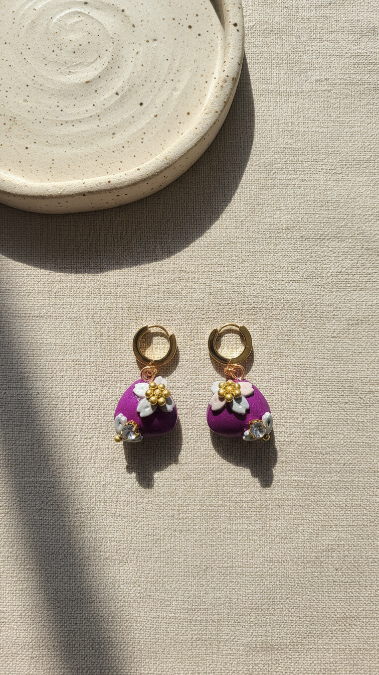 Pair of earrings with floral designs on a beige surface