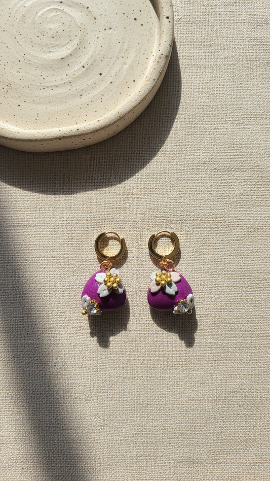 Pair of earrings with floral designs on a beige surface