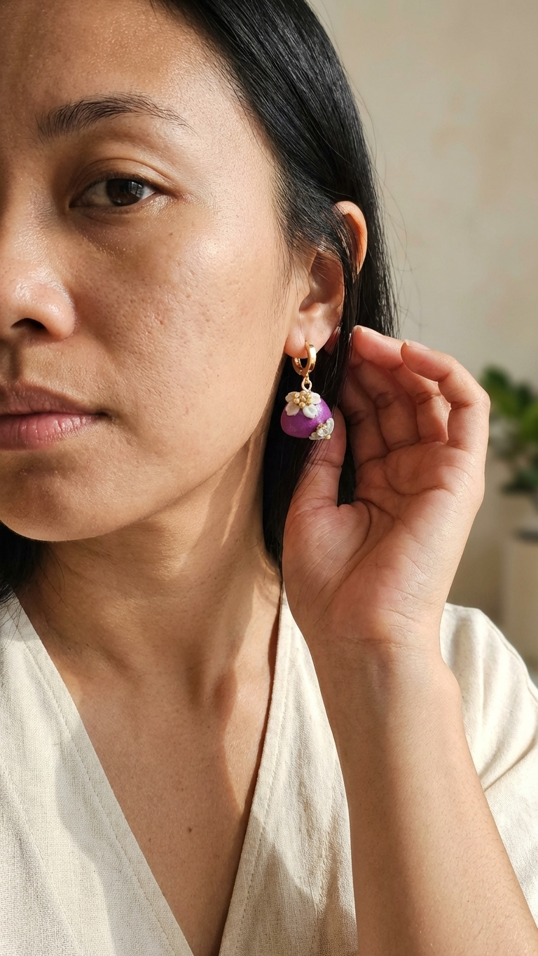 Woman wearing colorful earrings, adjusting them with her hand.