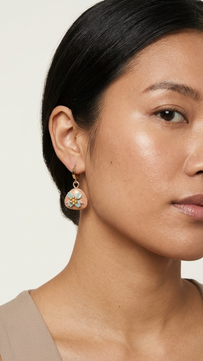 Close-up of a woman wearing a floral earring against a neutral background