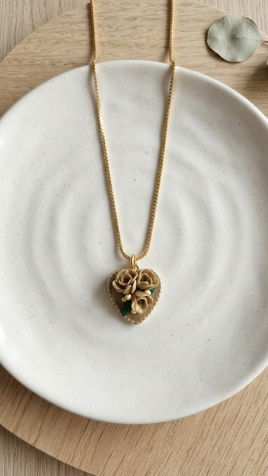 Gold heart-shaped necklace on a white ceramic dish with a wooden background