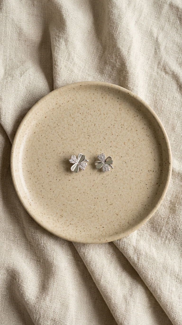four-leaf clover silver studs on a beige plate