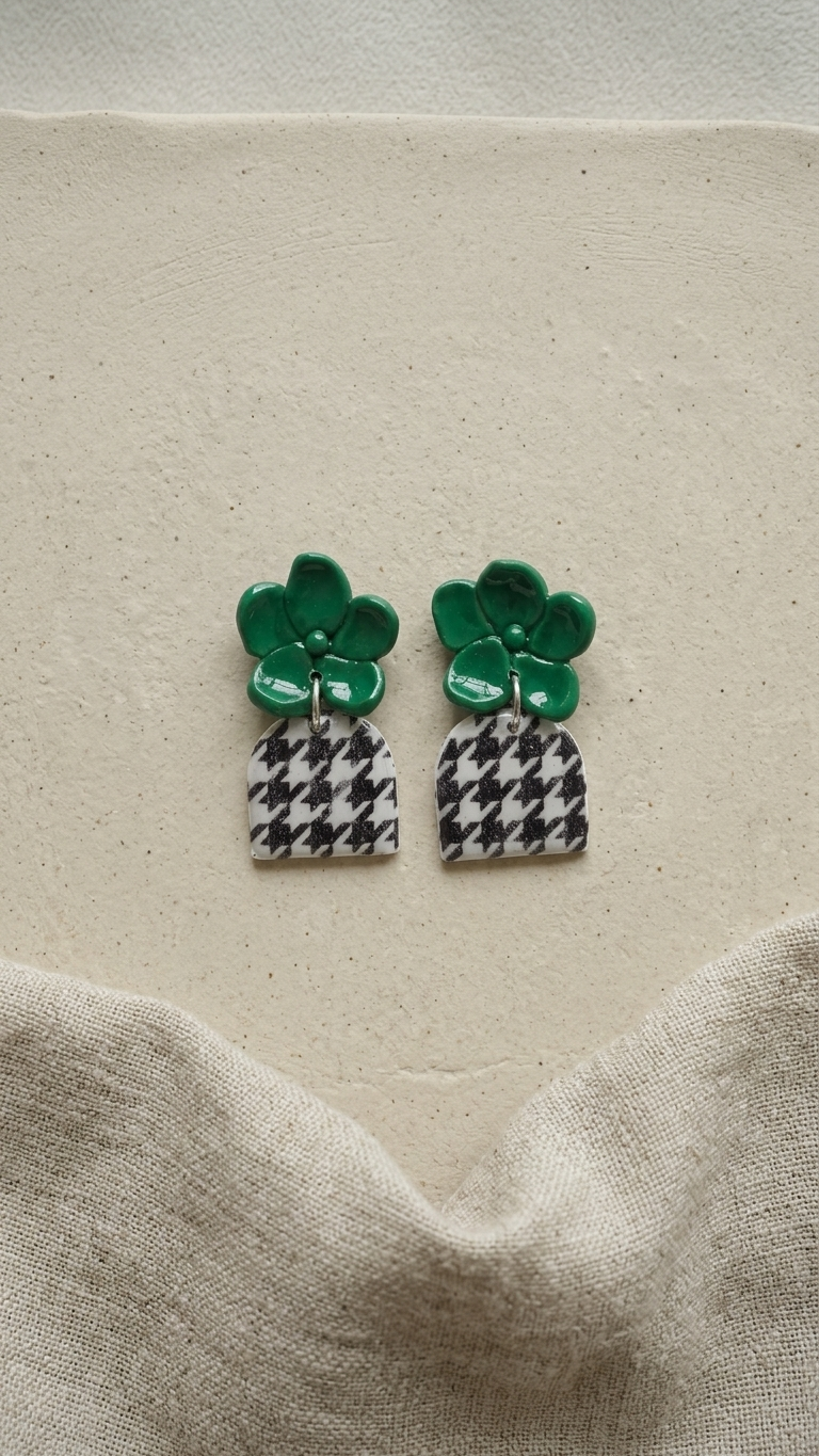 Pair of earrings with green tops and checkered bottoms on a beige fabric background