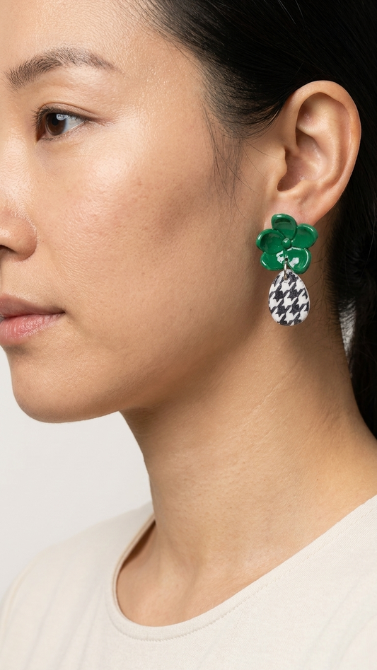 Close-up of a person wearing a green floral earring with a black and white checkered pendant.