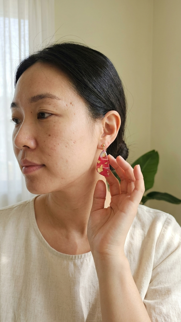 Woman wearing a red earring indoors with a neutral background