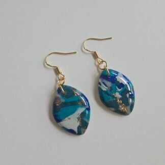 Pair of leaf-shaped blue marbled polymer clay earrings with gold-plated 925 silver hooks, featuring teal, navy, white, and subtle gold flecks on a light background.