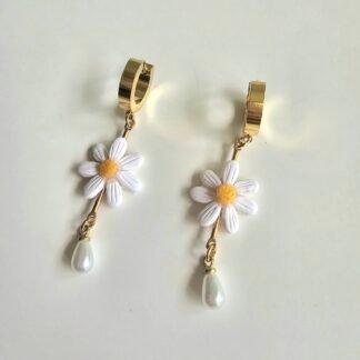 Handcrafted daisy drop earrings with white polymer clay petals, yellow centres, pearl teardrop accents, and gold-plated stainless steel huggie hoops, photographed on a soft neutral background.