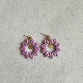 Lavender polymer clay petal wreath earrings with gold-plated stainless steel posts and a small gold charm, photographed on a neutral fabric background