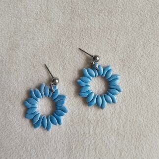 Handcrafted blue polymer clay floral wreath earrings with stainless steel posts on a soft neutral fabric background