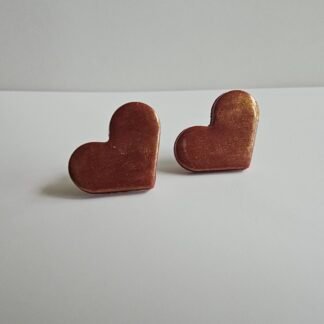 Handmade bronze-toned heart-shaped polymer clay stud earrings with a subtle shimmer, photographed on a clean neutral background.