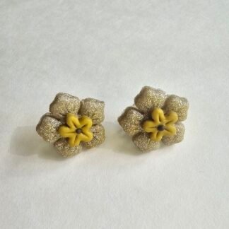 Handcrafted polymer clay floral stud earrings with champagne-gold textured petals and yellow centre on a neutral background