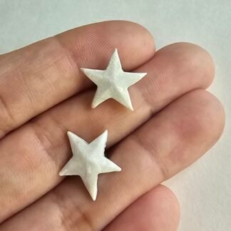 Handcrafted polymer clay white star stud earrings with a pearly finish resting on a hand