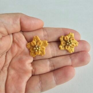 Handcrafted polymer clay golden floral stud earrings with layered petals and gold bead centre on a neutral background