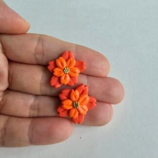 Handcrafted polymer clay coral and orange floral stud earrings with layered petals and gold bead centre, shown on hand