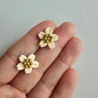 Handcrafted polymer clay pearl white floral stud earrings with gold bead centre on a light background