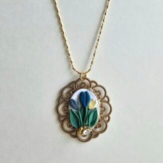 Handcrafted polymer clay floral pendant necklace with blue, green, and yellow tulip details, set in an ornate gold frame on a gold-plated 925 sterling silver chain by Haeng Bok Clay