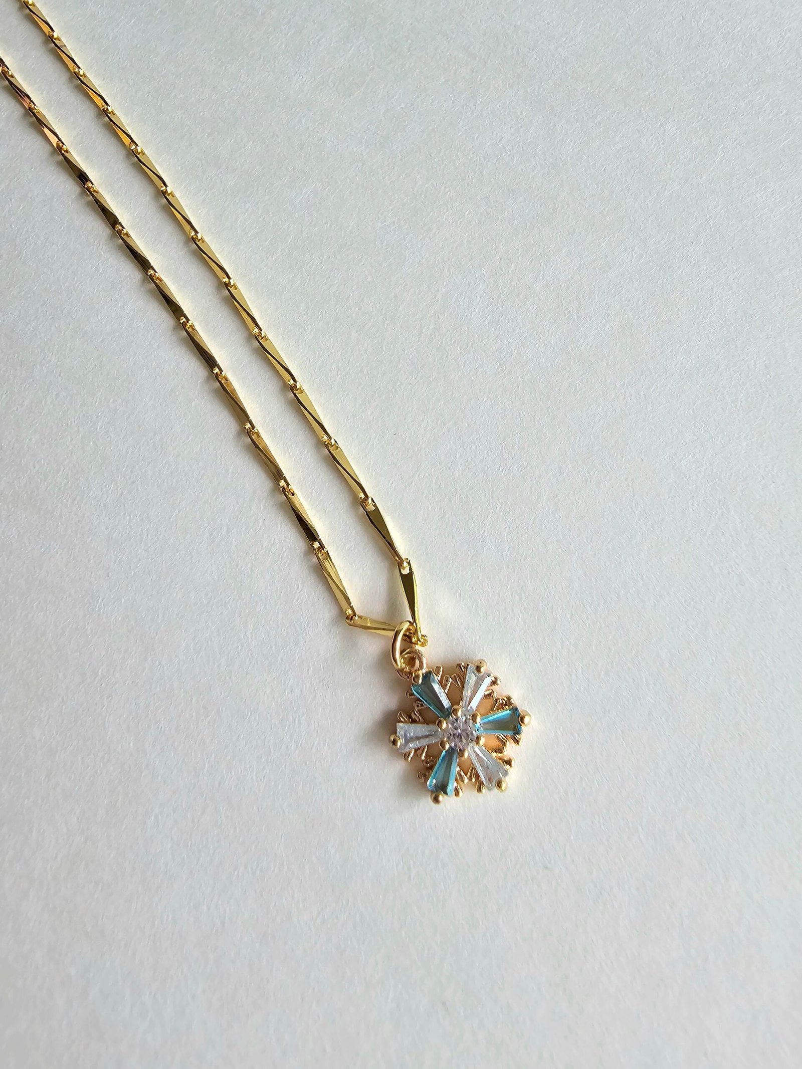 Gold plated 925 silver necklace with a snowflake-shaped crystal pendant featuring blue and clear stones on a delicate chain
