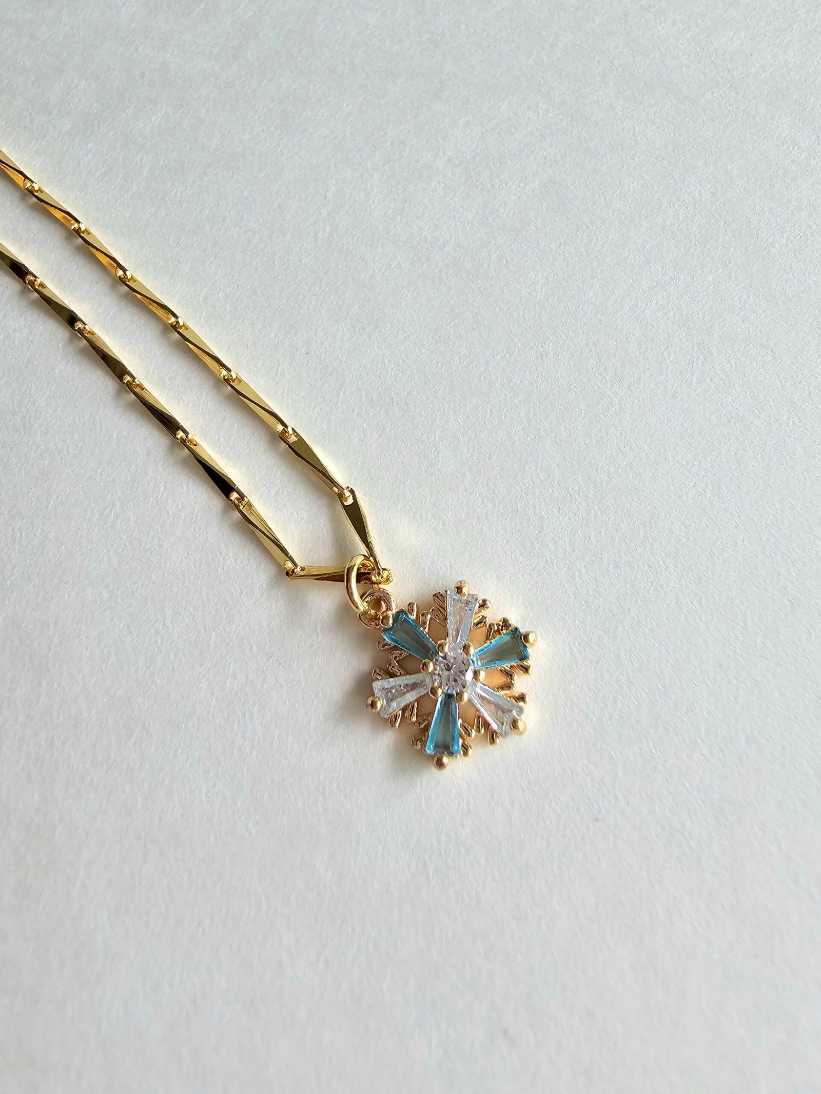 Gold plated 925 silver necklace with a snowflake-shaped crystal pendant featuring blue and clear stones on a delicate chain