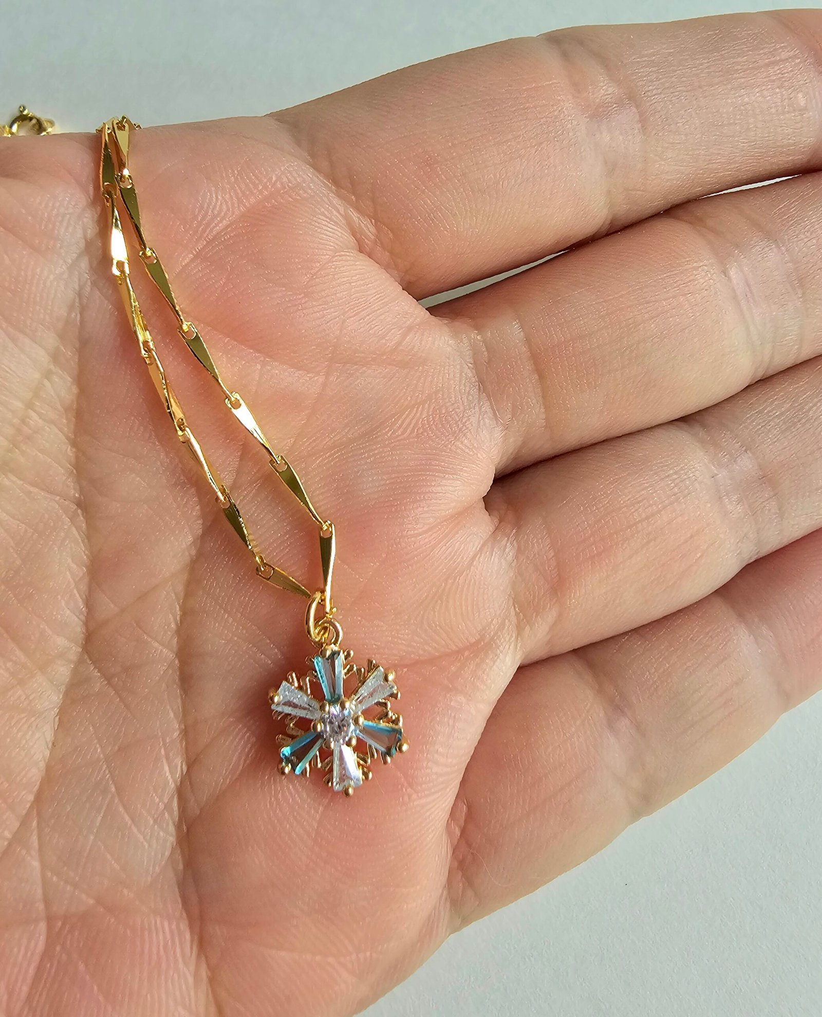 Gold plated 925 silver necklace with a snowflake-shaped crystal pendant featuring blue and clear stones on a delicate chain