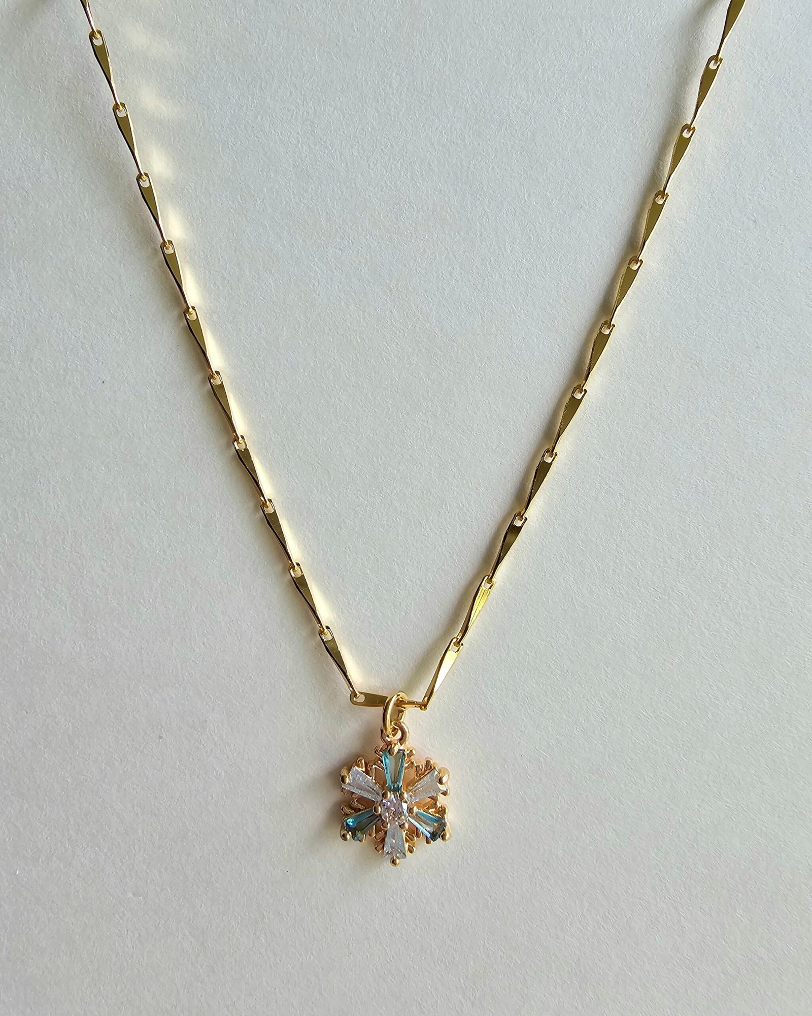 Gold plated 925 silver necklace with a snowflake-shaped crystal pendant featuring blue and clear stones on a delicate chain