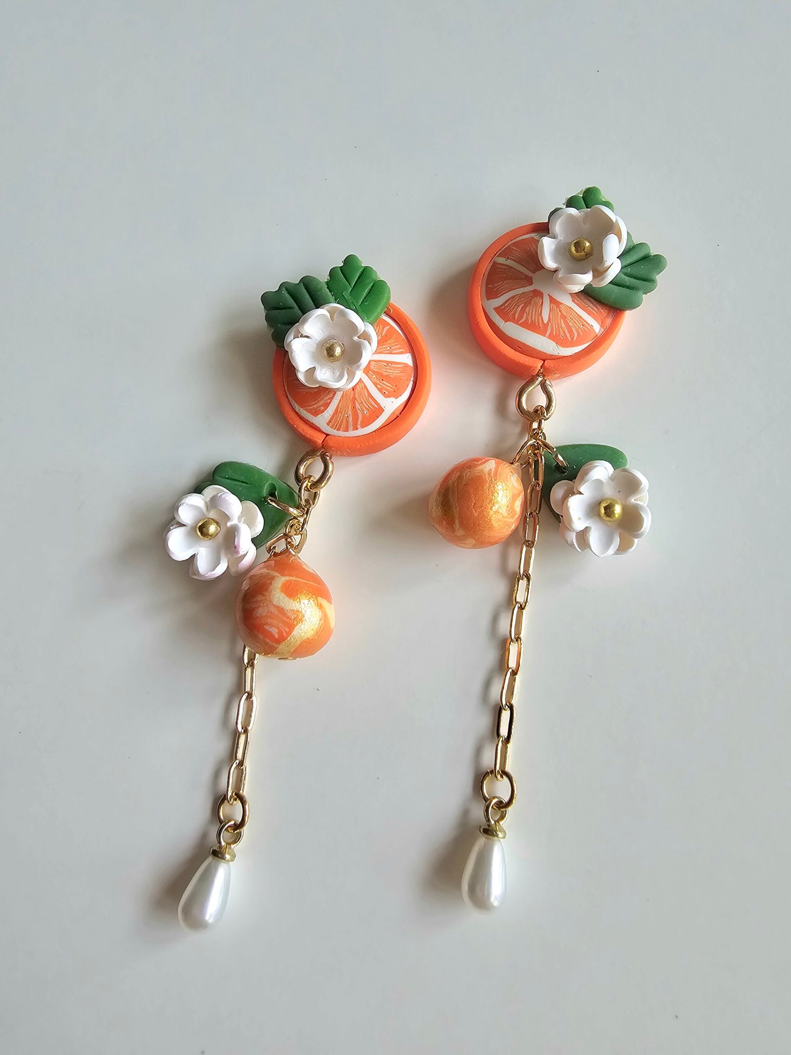 Handcrafted polymer clay citrus drop earrings with floral details, gold accents, and pearl drop by Haeng Bok Clay.